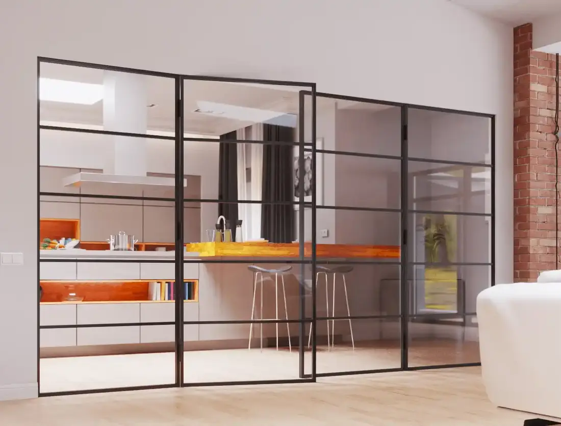 Schwarze Loft-Tür aus Glas mit Sprossen zwischen Wohnbereich und Küche, im Hintergrund Backsteinwand.