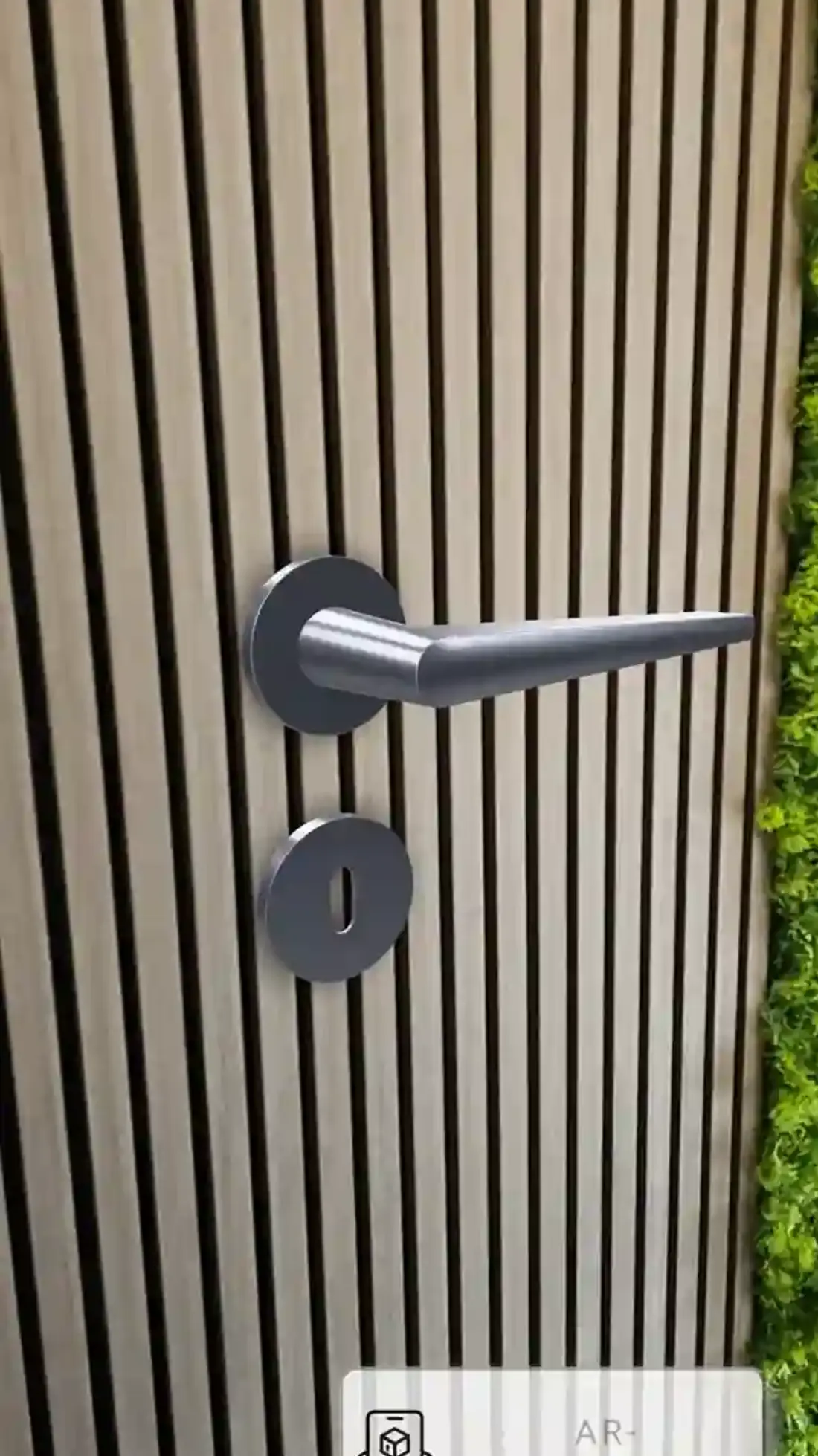 AR-Darstellung eines Türdrückers mit Schlüsselschild an einer senkrecht gerillten Holzwand, mit Button „AR-Darstellung“.