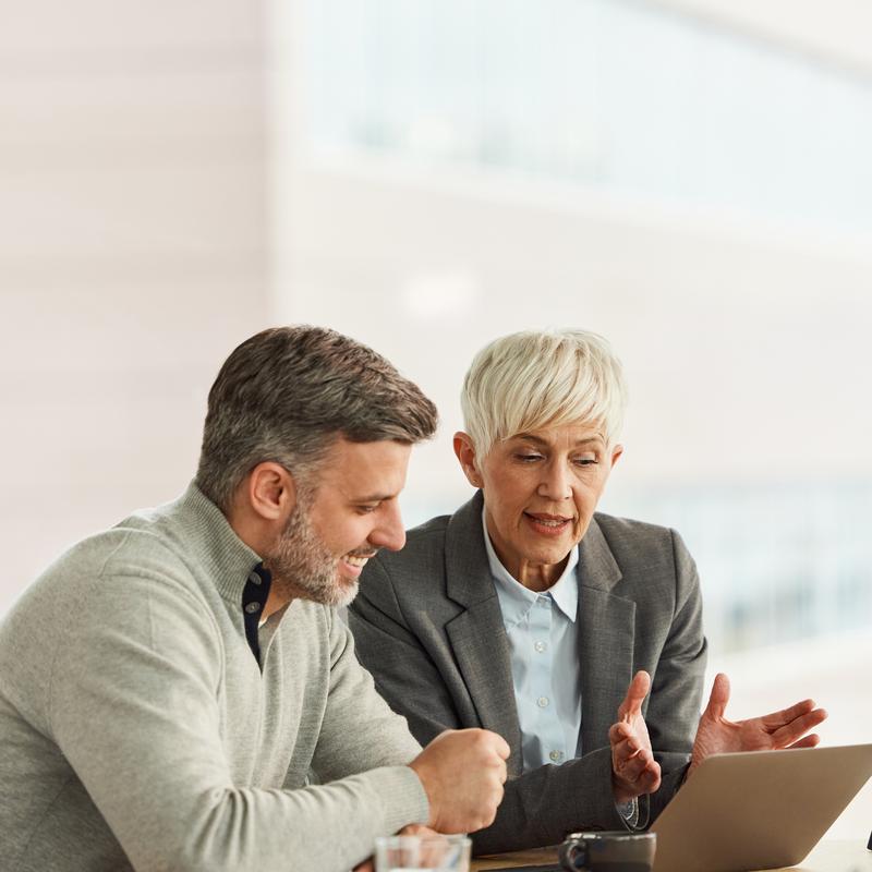 Vertriebsexpertin berät einen Kunden, während sie am Konferenztisch sitzen und auf einem Laptop eine 3D-Planung ansehen.