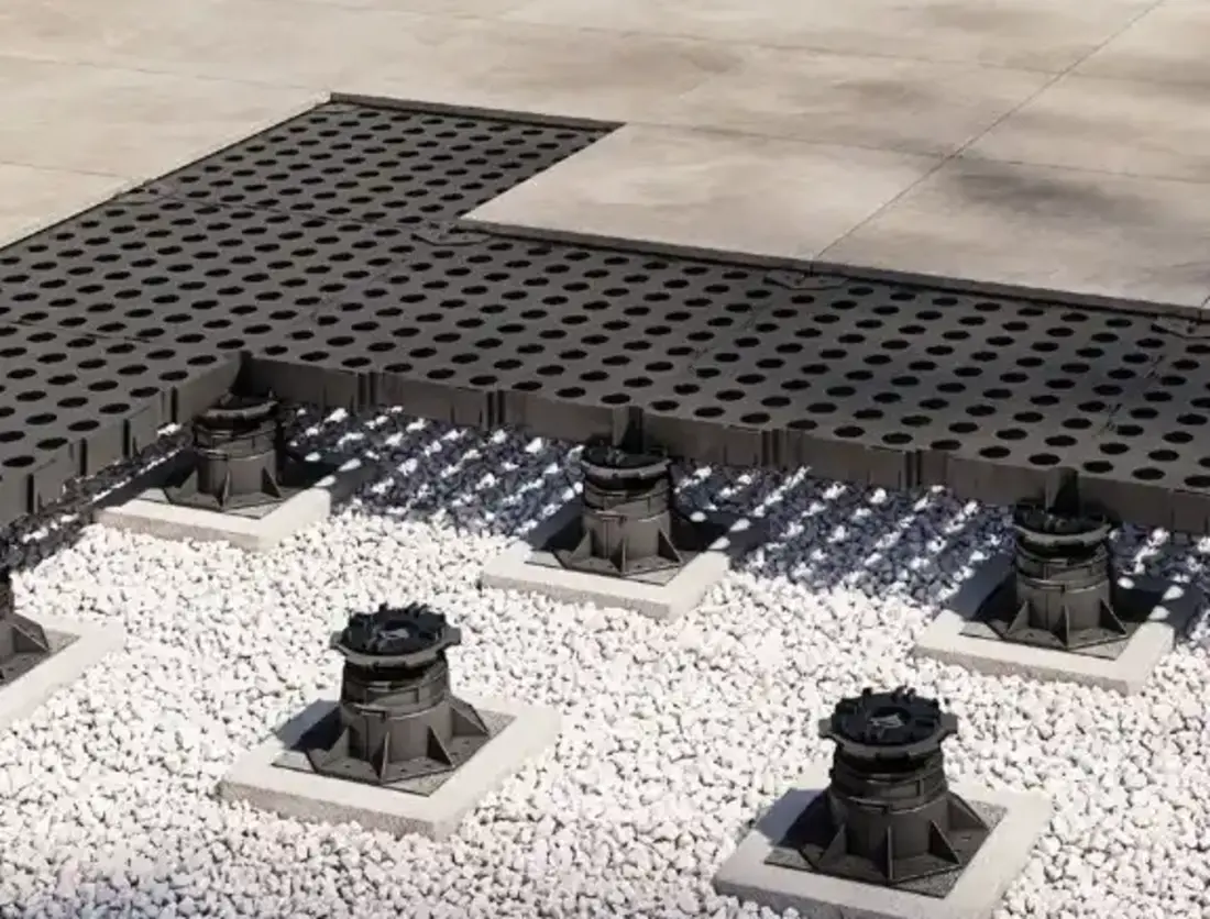 3D-Visualisierung einer Gitterrostplatte auf höhenverstellbaren Stelzlagern über einem Kiesbett, mit anschließender Steinplatten-Terrasse.
