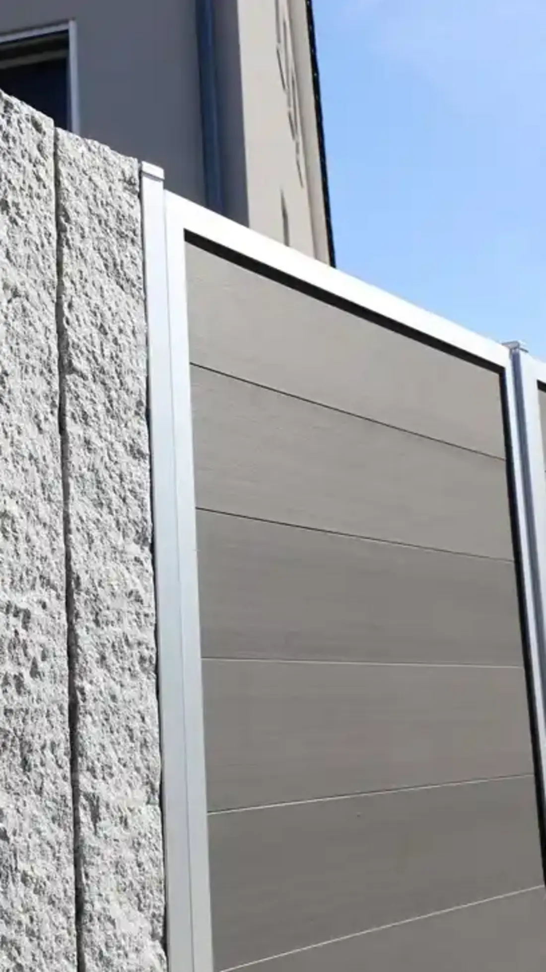 Modern privacy screen made of WPC in anthracite with aluminum frame and natural stone element durable and easy to maintain