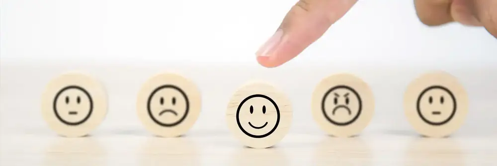 Holzchip mit lachendem Smiley im Fokus andere Chips mit Gesichtsausdrücken rundum Symbol für Kundenzufriedenheit